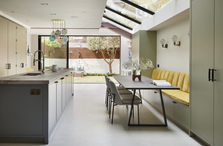 Exterior view of a modern London home with large glass doors opening to a landscaped garden.